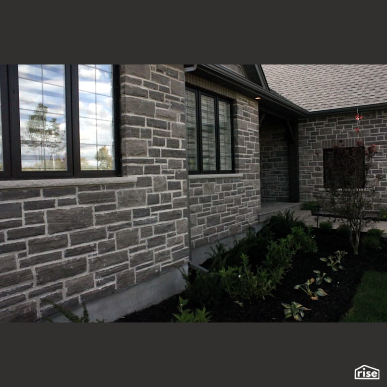 Front exterior stone siding with landscaped garden bed with Wood Mulch by Masonal Stone Inc