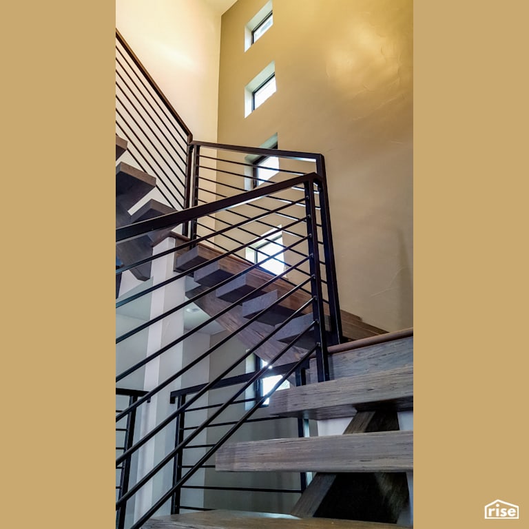 Main floor staircase and stairwell, featuring industrial metal railing and floating wood staircase with Fixed Window by Alpen High Performance Products