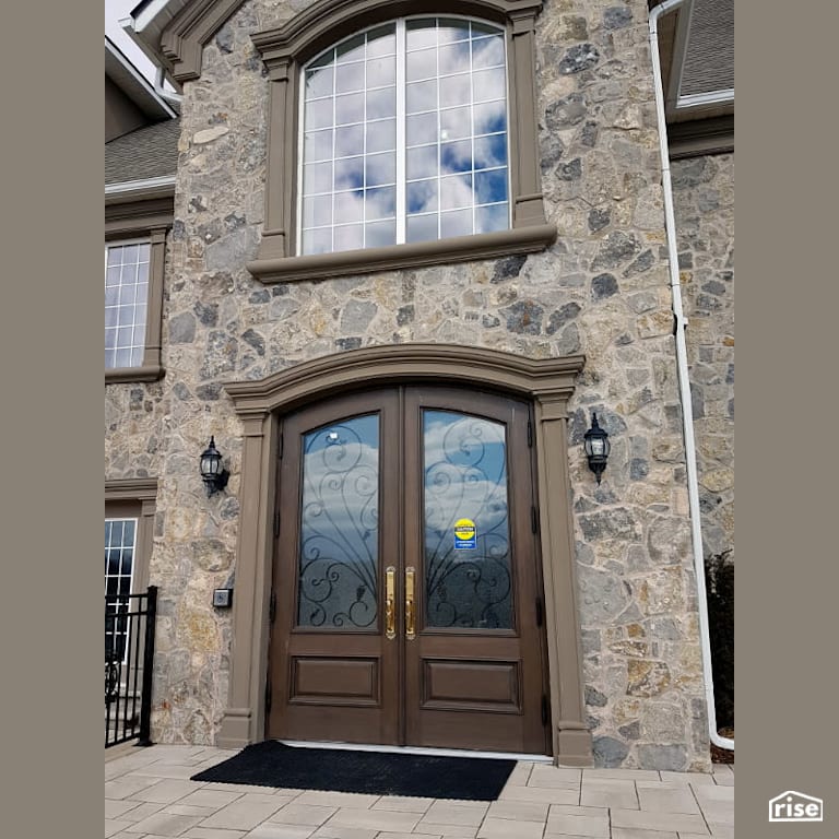 Two story stone building with large fixed window with Accent Outdoor Lighting by Masonal Stone Inc