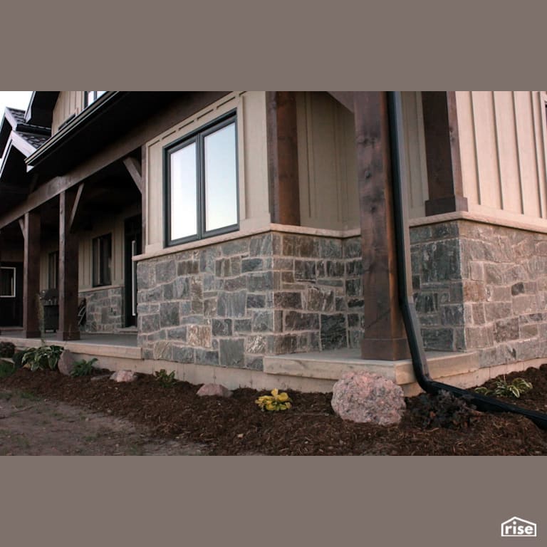 House with stone siding and mulched garden with Stone Siding by Masonal Stone Inc