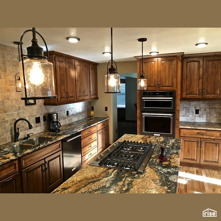 Warm kitchen with stainless steel appliances with Gas Range by Revolve Design Build