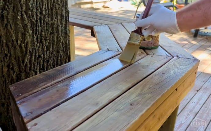 Applying wood stain to a bench
