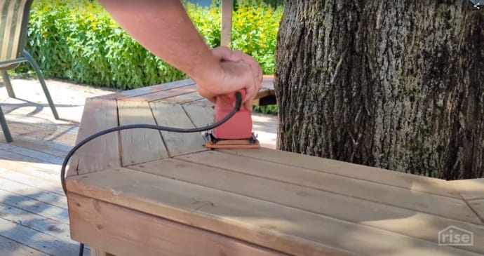 Sanding a wood bench before cleaning and staining
